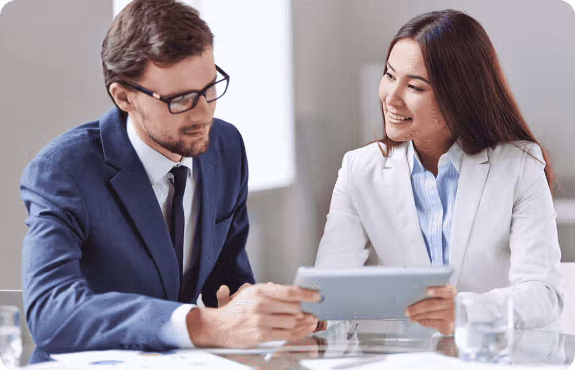Two professionals in business suits collaborate on a tablet, representing ccMonet’s experts. They leverage AI - powered tools to offer SMEs bookkeeping, reconciliation, and customized workflow solutions, with tax and compliance specialists ensuring financial accuracy and regulatory adherence.