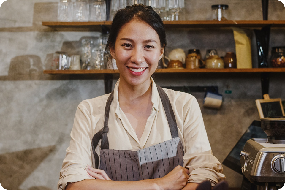 A woman in an apron stands in a café, representing F&B (food and beverage) SMEs. ccMonet’s AI - powered financial tools (bookkeeping, dashboards) and industry - tailored services, plus expert support (tax compliance, business registration), help such businesses manage finances efficiently.